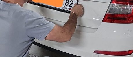 Person applying a license plate on a white Skoda Octavia.