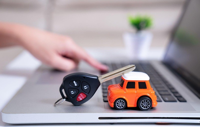 Close-up of a car key and a toy car placed on a laptop keyboard