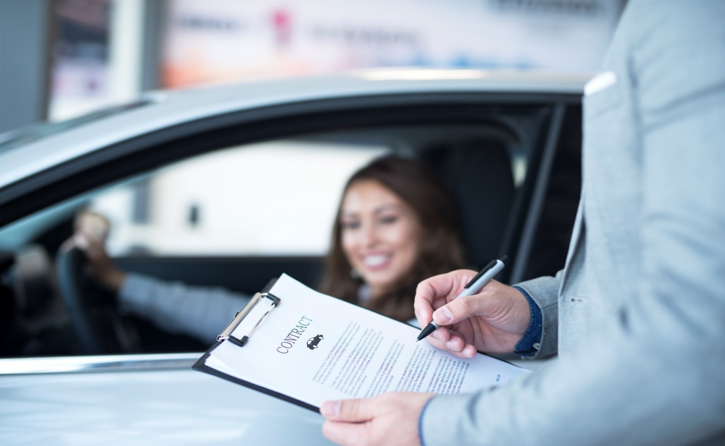 A person signing a car purchase contract