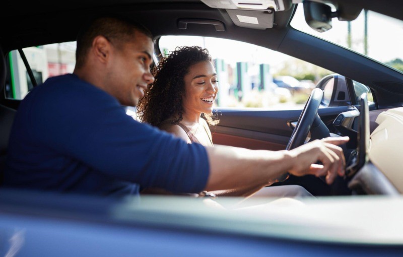 A man and woman smiling and interacting inside a car